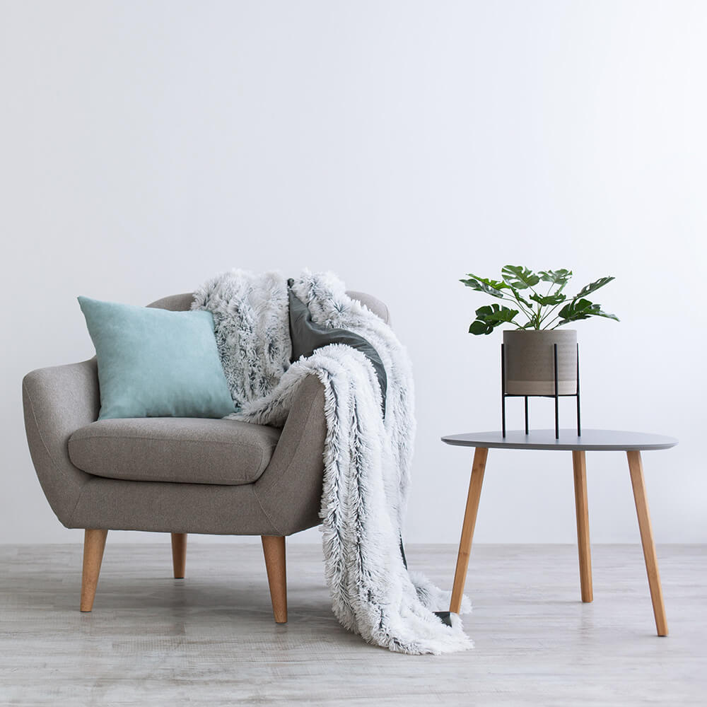 An armchair with green cushion and grey blanket